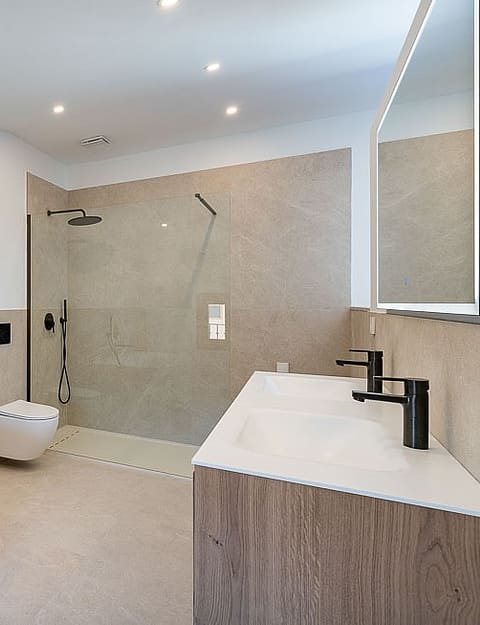 Contemporary bathroom with a white freestanding bathtub, walk-in glass shower, and wall-mounted vanity in a townhouse.