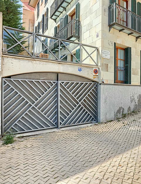 Exterior view of a residential building in the Old Town with a geometric metal garage gate and cobblestone street foreground.