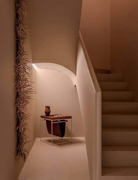 A minimalist white staircase with smooth plastered walls, an integrated handrail, and soft warm recessed lighting.