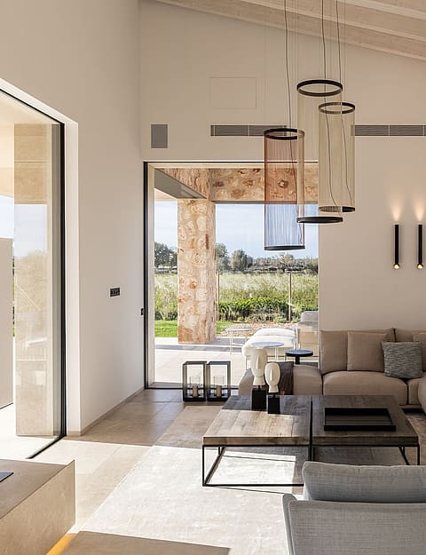 Living room with high vaulted ceiling, neutral sofa, and large glass doors opening to a terrace with mountain views.