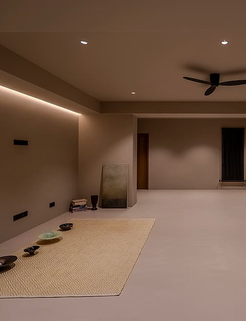 Large minimalist room with smooth beige walls, recessed ceiling lights, oak doors, and a black ceiling fan.