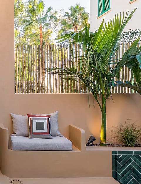 Modern outdoor shower with black fixtures next to a built-in masonry bench and tropical plants.