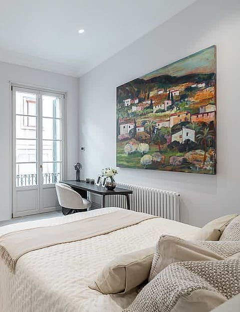 Bright bedroom with a double bed, mirrored wardrobe, and a small desk near window overlooking the Old Town.