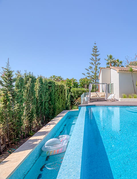 Exterior view of a Mediterranean villa with a rectangular swimming pool, wooden decking, and landscaped gardens in Santa Ponsa.