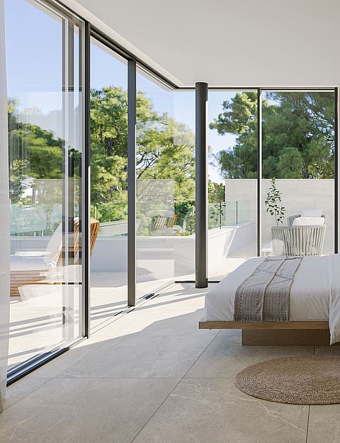 Modern master bedroom with floating bed, stone flooring, and floor-to-ceiling windows leading to a private terrace.