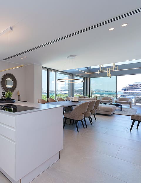 Cocina moderna con isla central blanca, suelos de baldosa clara y ventanales con acceso a la terraza.