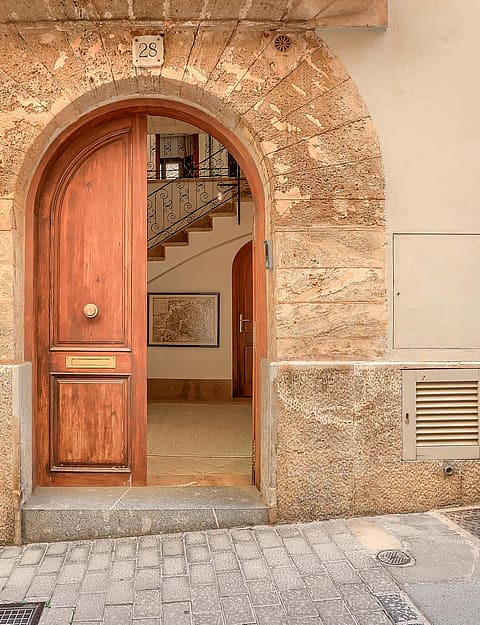 An arched timber front door set within a traditional natural stone facade on a cobblestone Old Town street.