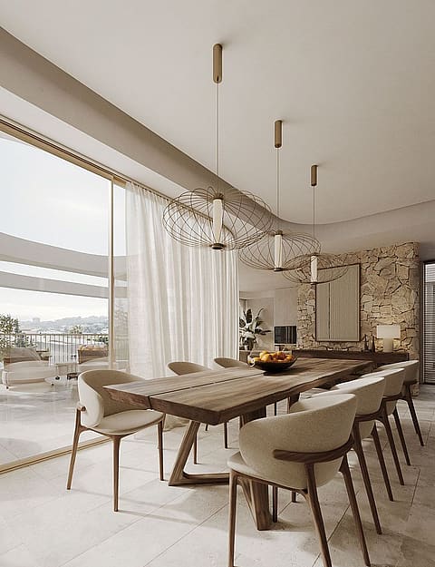 Dining area with long wooden table, cream upholstered chairs, and a natural stone feature wall, opening onto a balcony.