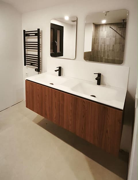 A modern bathroom featuring a wall-mounted wooden vanity with double sinks, two rectangular mirrors, and a black heated towel rail.