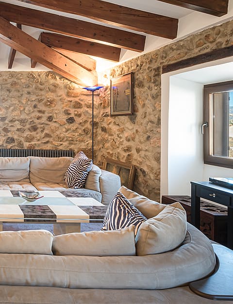 Living room with vaulted wood-beamed ceiling, stone feature wall and sectional sofa