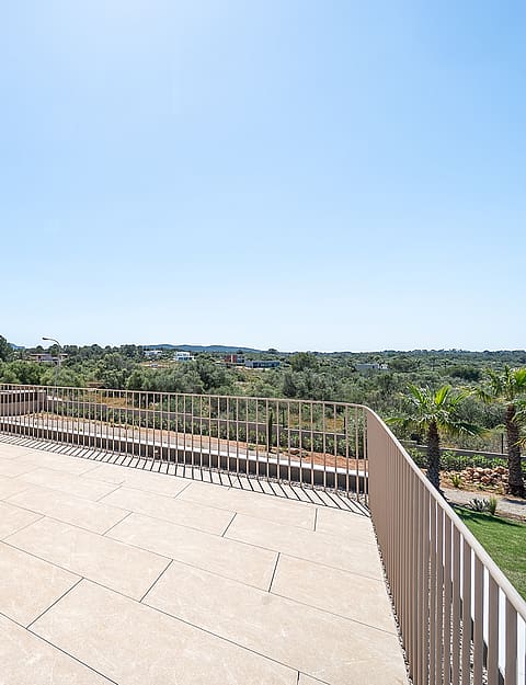A beige rooftop terrace featuring a metal spiral staircase and minimalist metal railings, overlooking a rural landscape.