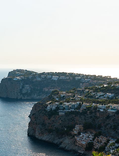 Aerial view of rocky coastline and cliffs meeting the Mediterranean sea in Port d'Andratx during daylight.