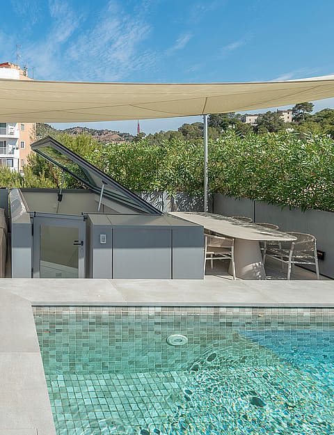 Rooftop terrace featuring a tiled swimming pool, modular beige sofa, dining area, and a beige shade canopy under clear skies.