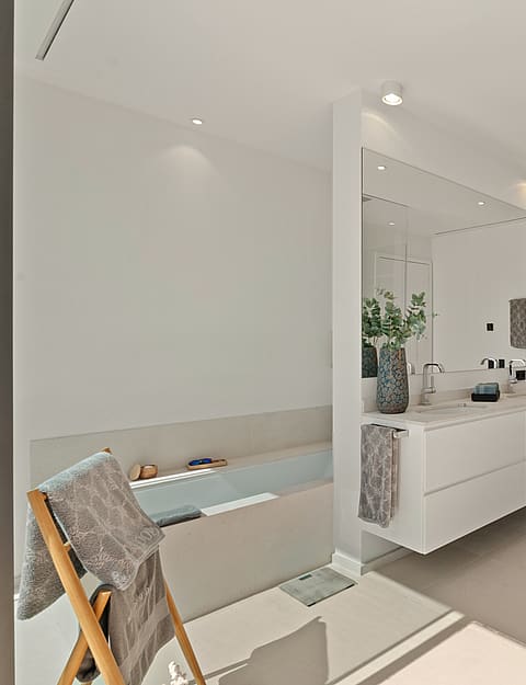 Minimalist bathroom featuring a floating white vanity, a walk-in glass shower, and a built-in bathtub on the left.