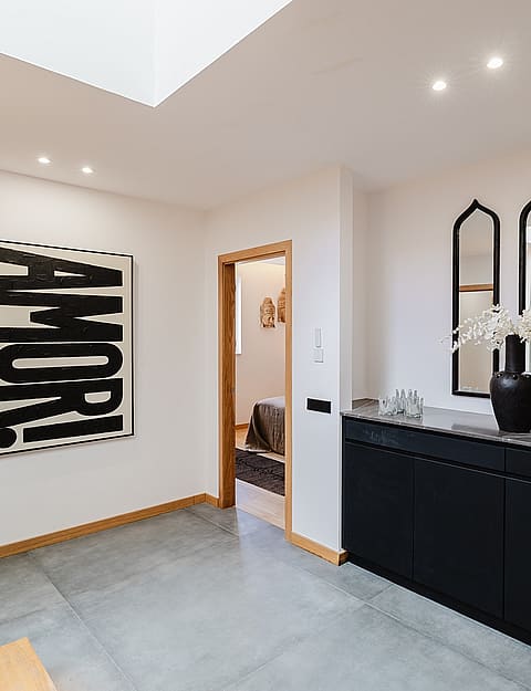 Interior hallway of an apartment in Santa Catalina with concrete floors, a black sideboard, and a skylight.