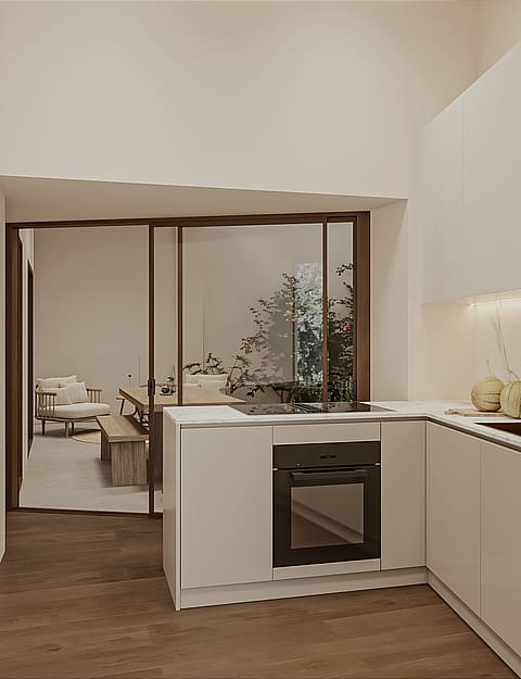 Compact kitchen with pale handleless cabinetry, marble splashback, brass tap, induction hob and integrated oven, glazed sliding partition to the living area.