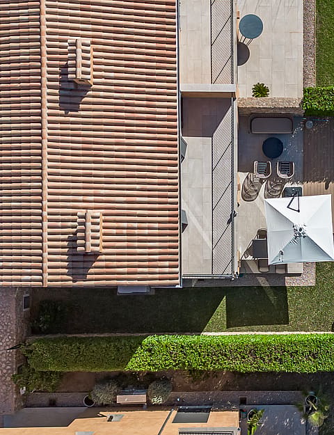 Top-down aerial view of a townhouse terrace, a rectangular swimming pool, and a manicured lawn enclosed by hedges.