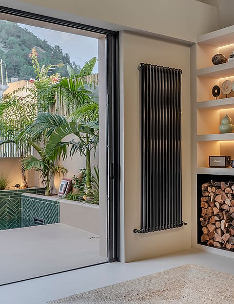 Modern living room featuring a glass-enclosed corner fireplace, built-in shelving, and sliding doors opening to a pool terrace.