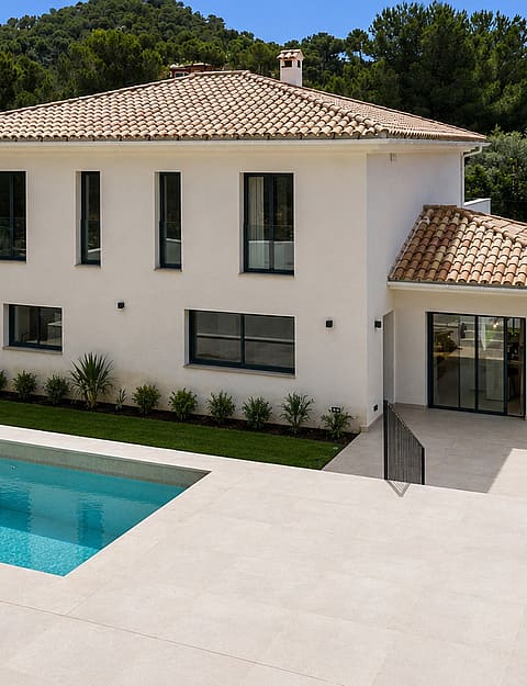 Exterior view of a white villa with clay-tiled roof, rectangular pool, and manicured lawns in Santa Ponsa.