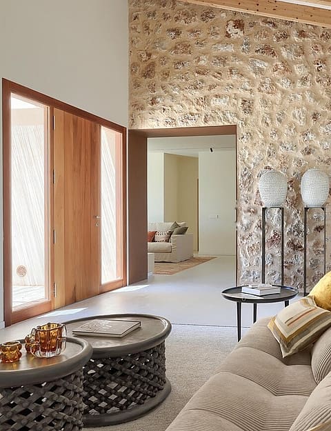 Interior view of a living area featuring a tall exposed stone feature wall, vaulted ceilings, and a light-colored sofa.