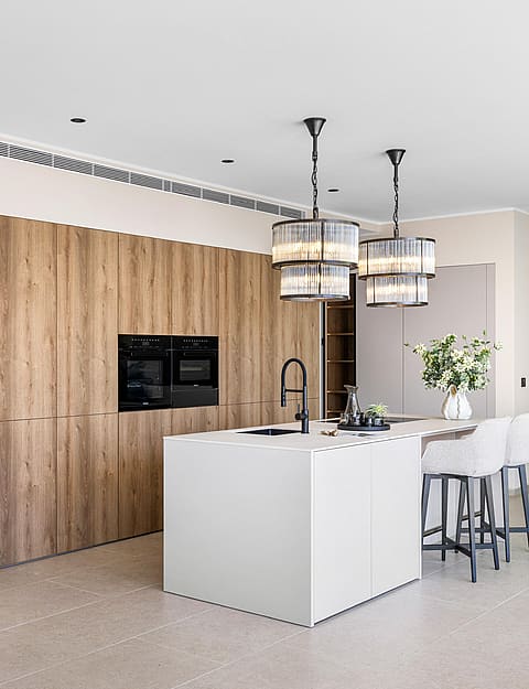 Fitted kitchen with full-height oak cabinetry, white composite island and two black-frame pendant lights