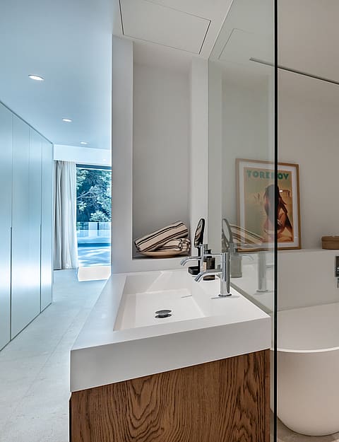 En-suite bathroom with large-format stone tiles, walk-in glass shower with rainfall head and vessel basin on timber vanity unit