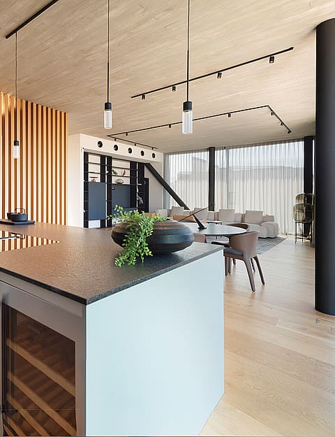 A modern kitchen island with a stone countertop and integrated wine fridge, set against a background of vertical wooden slats.