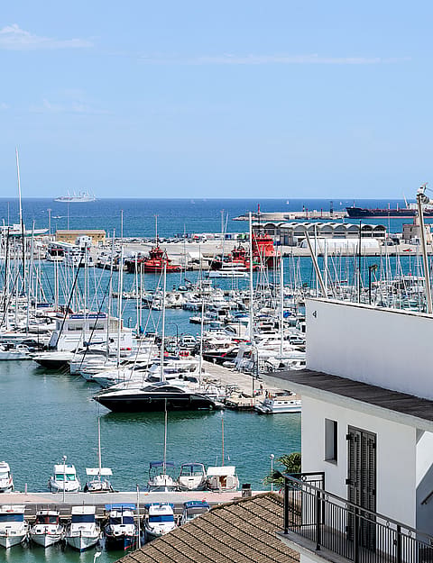 Elevated view overlooking a marina filled with yachts and boats under a bright blue sky.