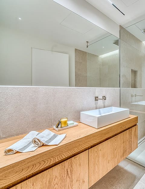 Contemporary bathroom featuring a floating light oak vanity, white vessel sink, large mirror, and walk-in glass shower.