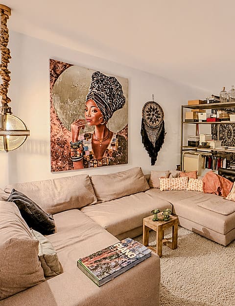 A spacious living room featuring a large beige sectional sofa, decorative wall art, and an adjacent open-plan dining space.