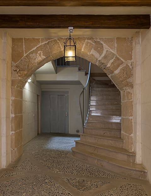 Entry hall featuring a traditional stone arch, exposed wooden beams, and pebble flooring in an 18th-century building.