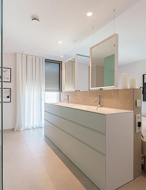 Dormitorio moderno con partición central, espejos dobles, ducha de cristal y cama minimalista.