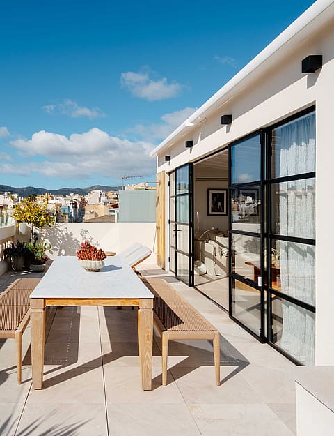 A rooftop terrace with a dining table and benches overlooking the Santa Catalina district under a clear blue sky.
