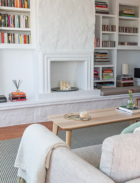 Living room interior featuring white built-in bookshelves surrounding a central fireplace and a light wood coffee table.