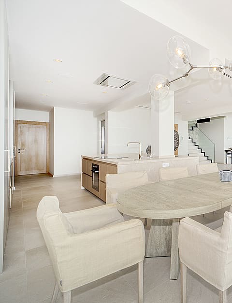 Bright open-plan space featuring an oval dining table, contemporary chandelier, and kitchen island with oak cabinetry.