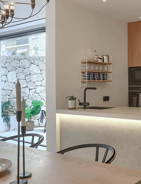 Contemporary kitchen featuring a terrazzo island with integrated under-counter lighting, wooden cabinetry, and dining area.
