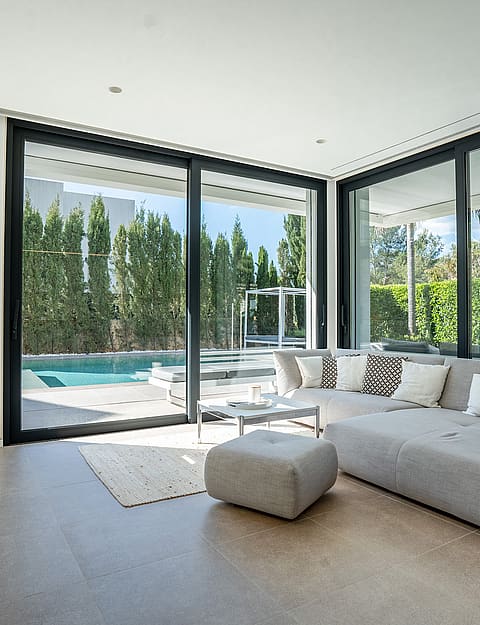 Living area with grey sectional sofa and sliding glass doors opening onto the swimming pool.