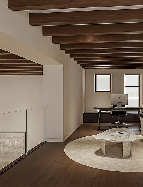 Mezzanine used as a home office with desk and sofa, glass balustrade and exposed dark timber beams overlooking the level below.