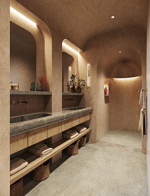 A master bathroom featuring a long stone vanity with double sinks, warm cove lighting, and an arched walk-in shower.