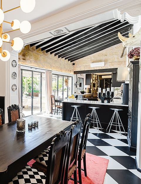 Dining area featuring black and white checkerboard tile flooring, a dark wood dining table, and a modern globe chandelier.