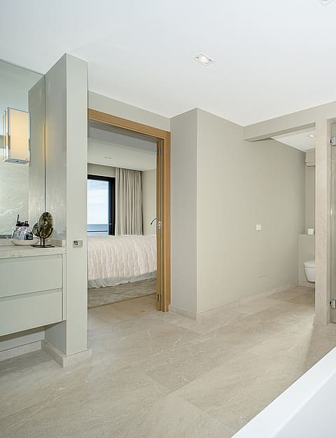 Modern master bathroom featuring a white soaking tub, walk-in glass shower, and neutral stone tiling with open layout.