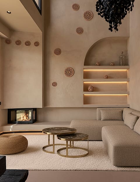 A modern living room with beige textured walls, a recessed fireplace, a modular sofa, and integrated shelving with warm lighting.