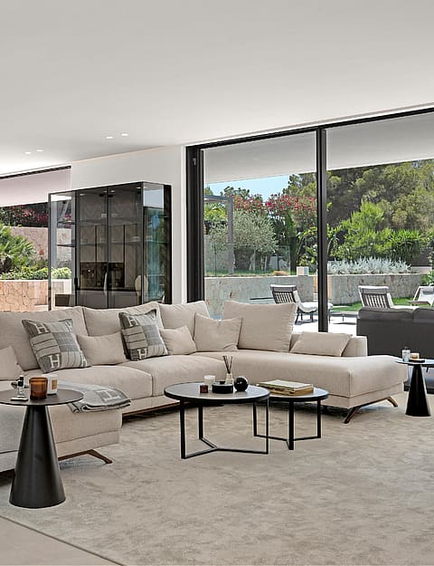 Open-plan living room with large sectional sofa, dining table and floor-to-ceiling glazing to garden