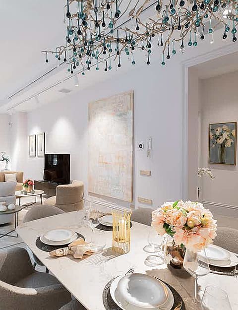Bright open-plan living area featuring a modern dining set with upholstered chairs and a sofa area with neutral textiles.