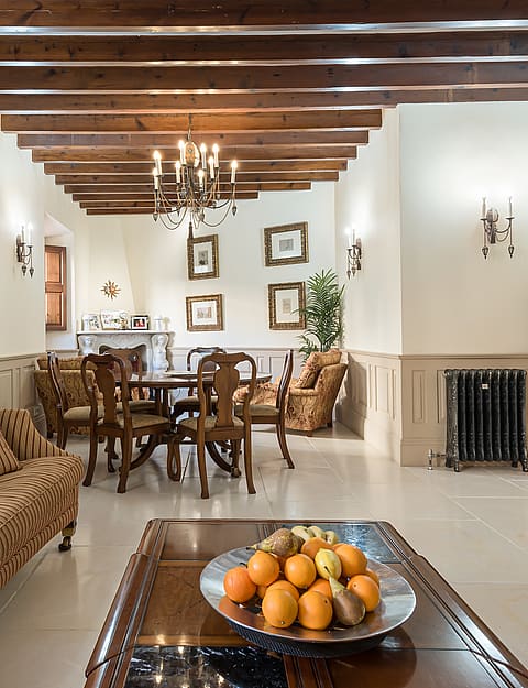 Living and dining area with striped sofa, wooden dining table and beamed ceiling