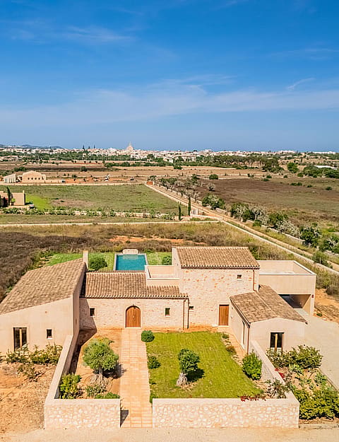 Aerial view of a traditional stone finca with tiled roofs, a private swimming pool, and landscaped gardens in a rural setting.