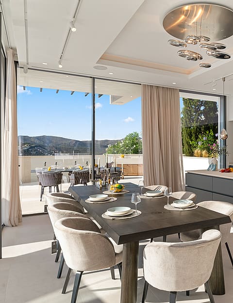 Modern open-plan kitchen and dining area with dark cabinetry, large center island, and views to an outdoor terrace.