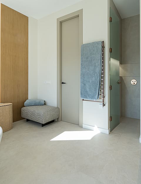 A bright bathroom featuring a white freestanding bathtub, a stone double vanity with bronze fixtures, and warm wood accents.