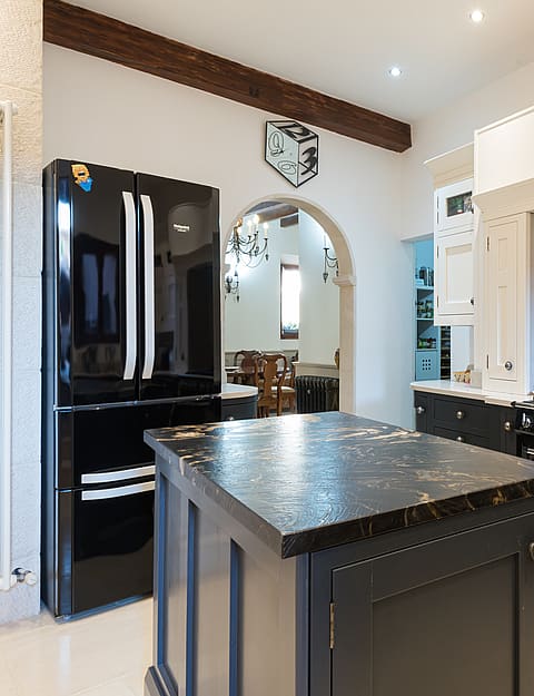 Kitchen with black cabinetry, marble-topped island and black SMEG range cooker