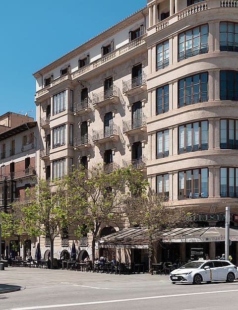 Street-level view of a classic beige residential building on a corner in Palma with multiple windows and balconies.